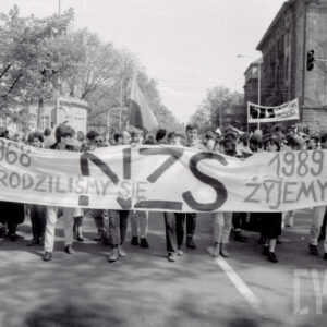 tłum ludzi idzie ulicą trzymając przed sobą długi transparent