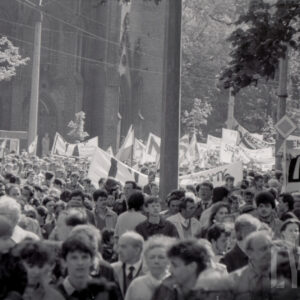 tłum ludzi z transparentami idzie ulicą, w głębi kościół