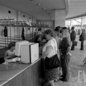 półokrągły hol, z lewej lada, za nią puste wieszaki, przy ladzie stoją ludzie