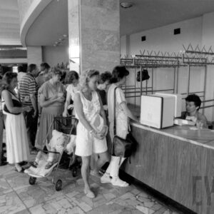 półokrągły hol, z prawej lada, za nią puste wieszaki, przy ladzie stoją ludzie