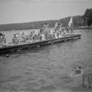duża grupa ludzi na drewnianym pomoście na jeziorze, w głębi zalesiony brzeg