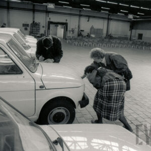 duża hala, w niej ludzie oglądający zaparkowane w rzędach samochody osobowe