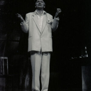 mężczyzna stoi na scenie z wyciągniętymi ku górze rękoma