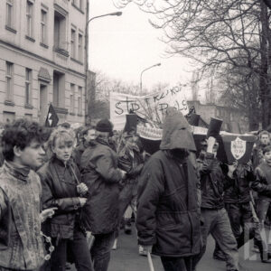 duże zgromadzenie osób z transparentami na placu, w głębi budynki