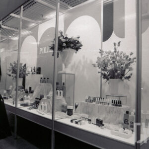 stoisko z kosmetykami ozdobione kwiatami w wazonach, z lewej stoi kobieta