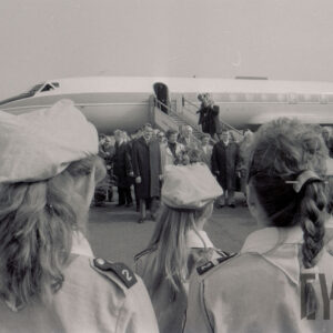 na pierwszym planie harcerki stojące tyłem, w głębi samolot, przed nim stoją ludzie