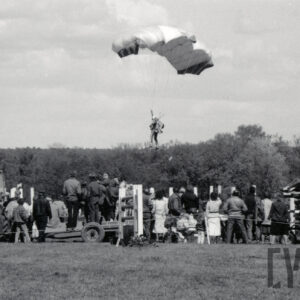 duża grupa ludzi obserwuje skok spadochroniarza, z lewej traktor