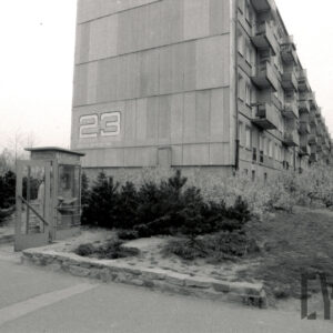 pięciokondygnacyjny blok mieszkalny z wielkiej płyty, na pierwszym planie budka telefoniczna