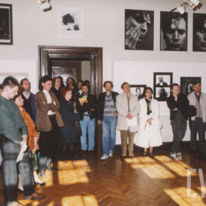 duż grupa ludzi stoi w pomieszczeniu, na którego ścianach wiszą duże zdjęcia