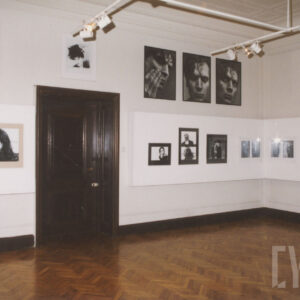 pomieszczenie galerii z drzwiami, drewnianym parkietem i zdjęciami o różnych formatach na ścianach