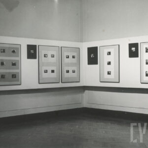 czarno-białe wnętrze sali ekspozycyjnej z fotografiami umieszczonymi w ramach, w każdej ramie znajduje się kilka fotografii