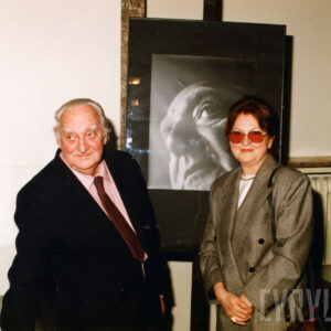 mężczyzna i kobieta stoją na tle sztalugi ze zdjęciem twarzy mężczyzny