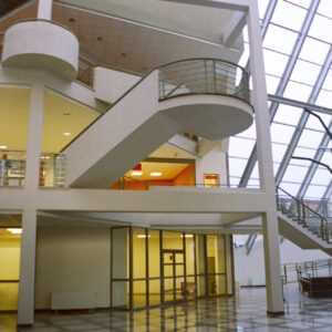 przestrzenne, jasne wnętrze budynku o nieregularnej bryle z antresolami, schodami i dużymi przeszkleniami