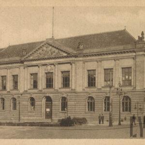 monumentalny, klasycystyczny budynek z kolumnowym wejściem i dekoracyjnym frontonem; przed budynkiem latarnie uliczne, a na chodniku przechodzący ludzie