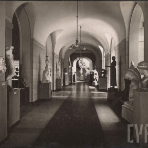 długi, sklepiony ciąg komunikacyjny z arkadami, po obu stronach ustawione rzeźby na postumentach, w głębi schody, z sufity zwisają lampy