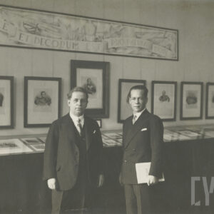 dwóch mężczyzn w średnim wieku, ubranych w garnitury, pozujących do fotografii na tle gablot wystawowych