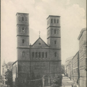 masywna budowla sakralna w neoromańskim stylu, z dwiema wieżami prosto zakończonymi po bokach fasady, po lewej i prawej stronie budowli ulica