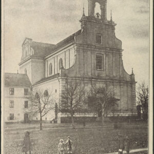 budowla sakralna w stylu barokowym, z lewej przylegający do niej trzykondygnacyjny budynek, przed budowlą drzewa, na pierwszym planie kilka osób, w tym dwójka dzieci