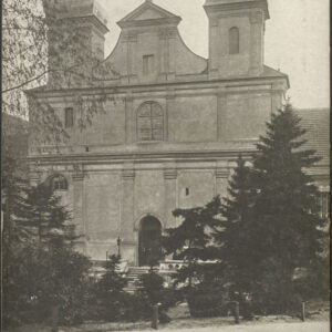 barokowa budowla sakralna z dwiema wieżami, przed nią drzewa, na pierwszym planie brukowana ulica