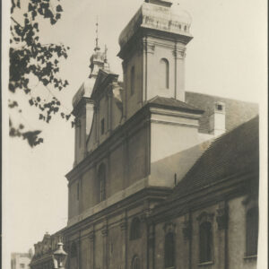 barokowa budowla sakralna z dwiema wieżami, po obu stronach przylegające do niej zabudowania, na pierwszym planie latarnia uliczna, u góry zdjęcia zwisające gałęzie drzewa