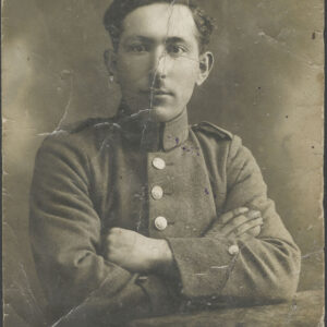 młody mężczyzna z włosami zaczesanymi do tytułu i niedużymi wąsami, pozuje do fotografii ubrany w mundur wojskowy