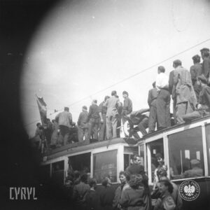 duża grupa ludzi stojąca na dachu tramwaju oraz wokół niego