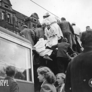 kilka osób wchodzi na dach tramwaju, część stojących im pomaga