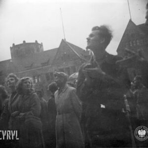 grupa osób stoi, dwóch mężczyzn klaszcze w dłonie (jednemu z nich widać tylko ręce złożone do oklasku