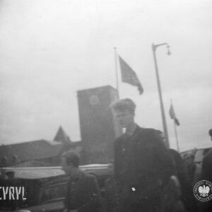 kilka osób ujętych na zdjęciu od pasa w górę, w głębi potężny budynek z wysoką wieżą