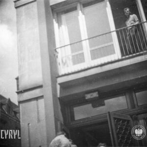 młody mężczyzna stoi w oknie nad wejściem do budynku
