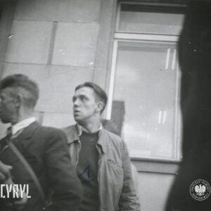 dwóch mężczyzn na tle fragmentu elewacji z oknem