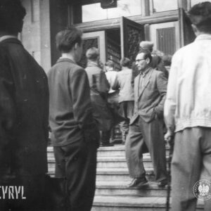 grupa mężczyzn wchodzi przez otwarte drzwi do budynku