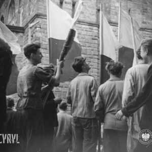 kilka osób z flagami stoi przed okazałym gmachem