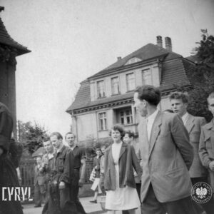 grupa ludzi idzie ulicą, w głębi wille miejskie