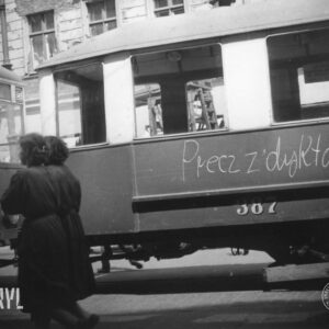 tramwaj z wymalowanym hasłem, w głębi kamienica z odrapanym tynkiem