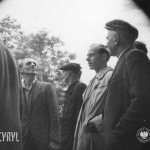 kilku mężczyzn stoi w grupie, w głębi drzewa