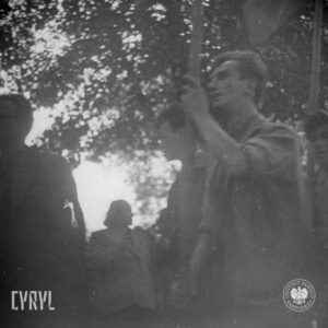 grupa młodych mężczyzn ujętych od pasa w górę, dwóch mężczyzn trzyma w rękach drzewce, na których prawdopodobnie powiewają flagi