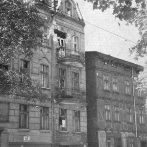 kamienica ze śladami ostrzału, duże uszkodzenia przy oknie balkonowym
