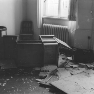 wnętrze biura,  połamane biurko leży na podłodze, z prawej przewrócone krzesło, porozrzucane fragmenty mebli biurowych