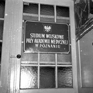 fragment drzwi z szybkami, na nich metalowa tablica informacyjna