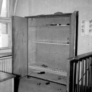 otwarta , pusta, drewniana szafa, z prawej fragment drewnianej barierki odgradzającej pomieszczenie