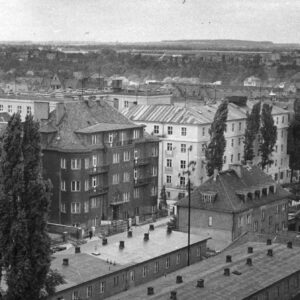 widok z lotu ptaka, na pierwszym planie parterowa zabudowa magazynów i garaży, w głębi kilkupiętrowe kamienice stojące przy ulicy