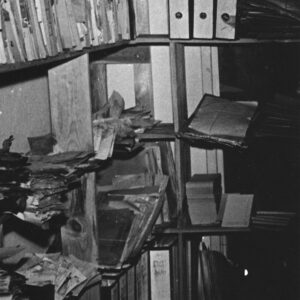 fragment pomieszczenia biurowego, na półkach napalone akta