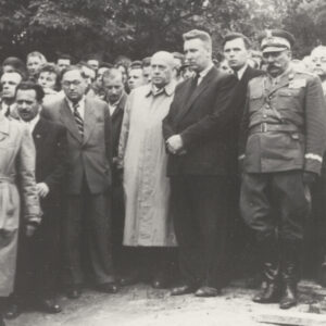 duża grupa ludzi, z prawej mężczyzna w mundurze, z narożniku fragment trumny