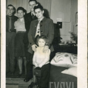 czwórka ludzi w średnim wieku, dwie kobiety i dwóch mężczyzn, oraz dziecko pozują do fotografii we wnętrzu mieszkalnym, po prawej fragment kanapy , na niej wzorzyste poduszki, w tle zasłona okienna