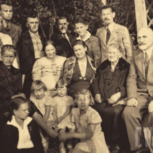 grupa ludzi w różnym wieku pozująca do fotografii; w tle drzewa i fragment altany ogrodowej