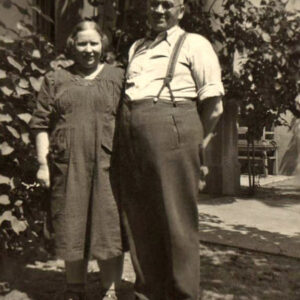 dwójka starszych osób - kobieta i mężczyzna, pozująca do fotografii na tle drzew w ogrodzie