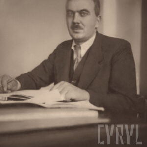 mężczyzna w średnim wieku ubrany w garnitur, pozujący do fotografii siedząc przy biurku