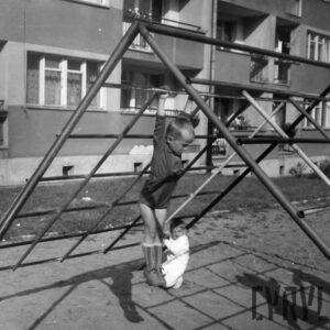 dzieci bawiące się na drabinkach na placu zabaw między blokami mieszkalnymi