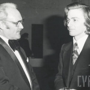 dwóch mężczyzn (z prawej młodszy mężczyzna) stoi i rozmawia ze sobą